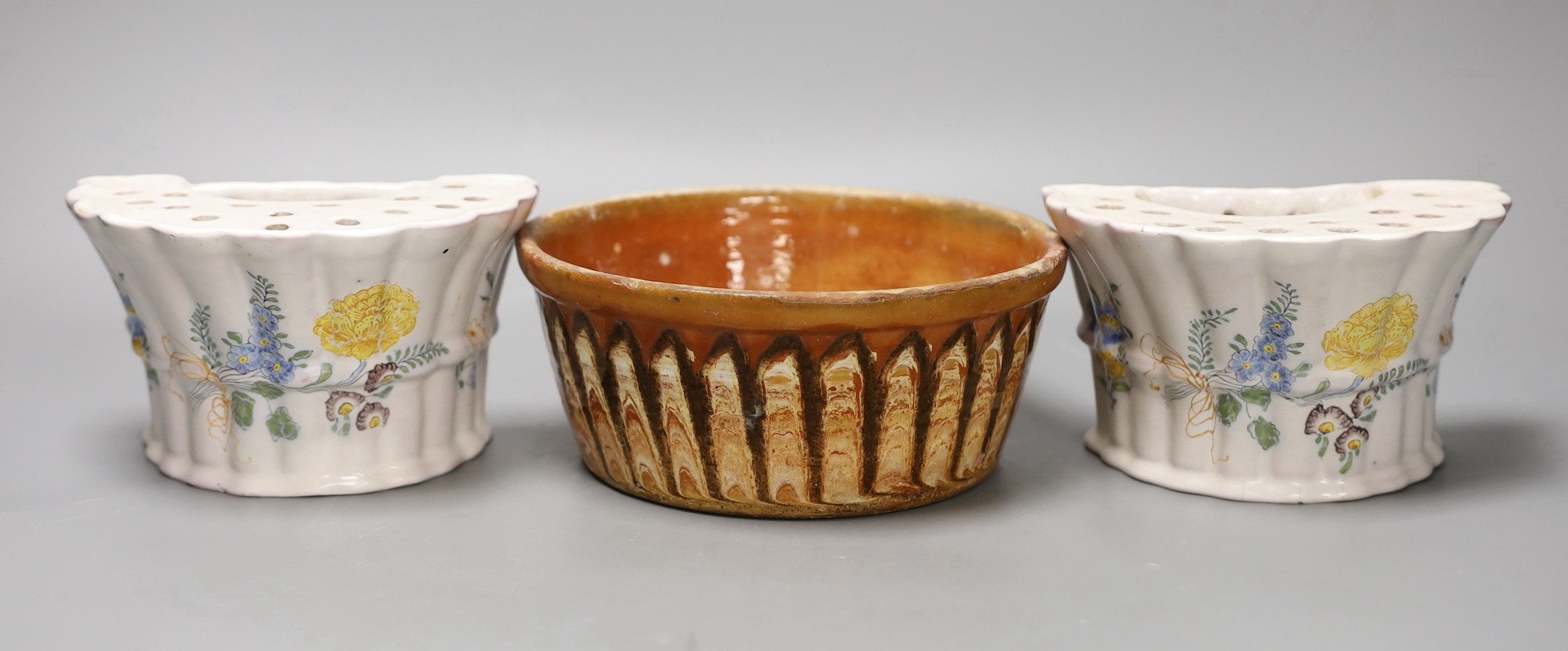A Slipware conical bowl, 18th / 19th century, flaking to decoration, 19cm diameter, together with a pair of German faience flower decorated bough pots, late 18th century, 15.5cm wide